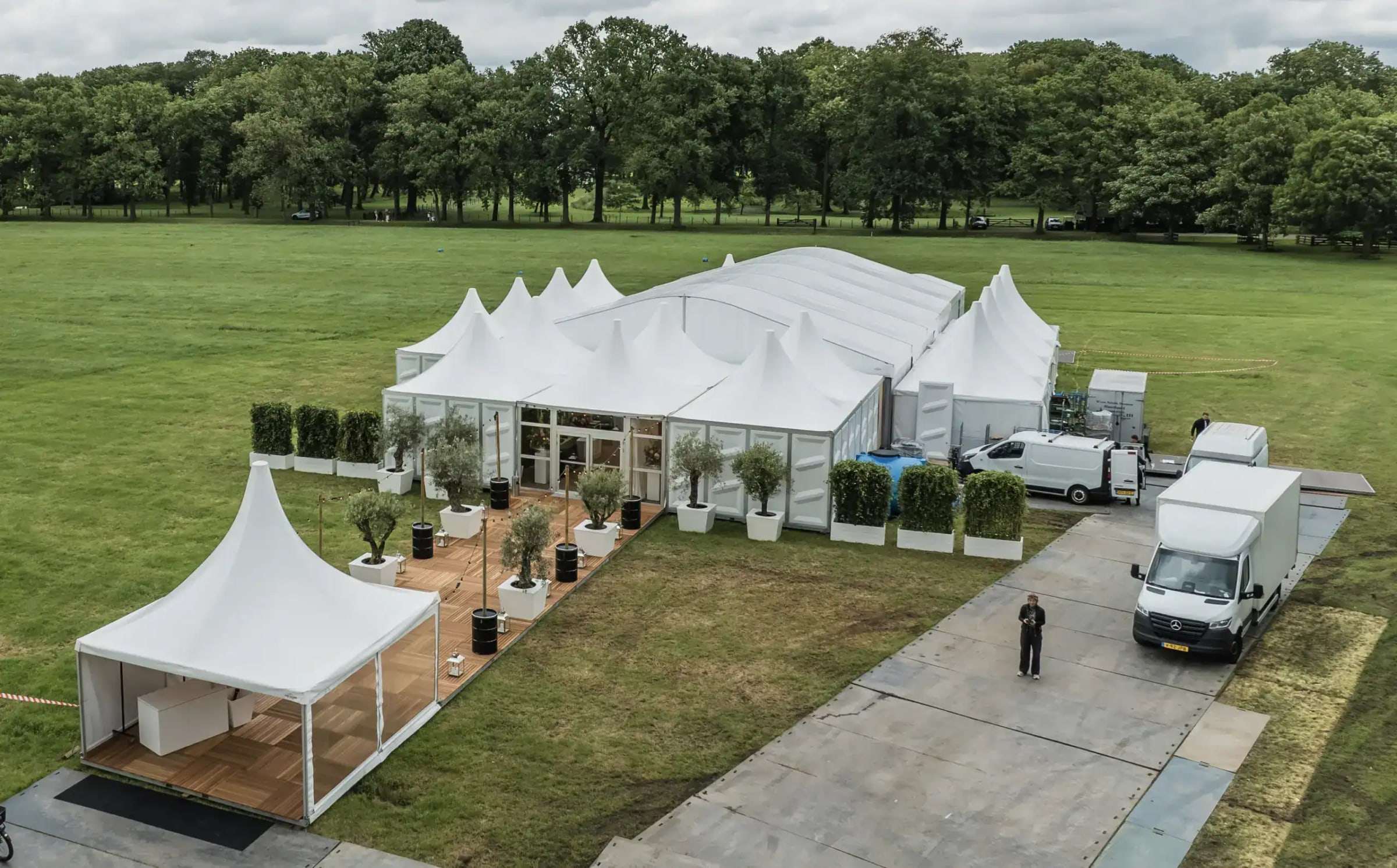 Luchtfoto van een evenement met witte tenten op een grasveld