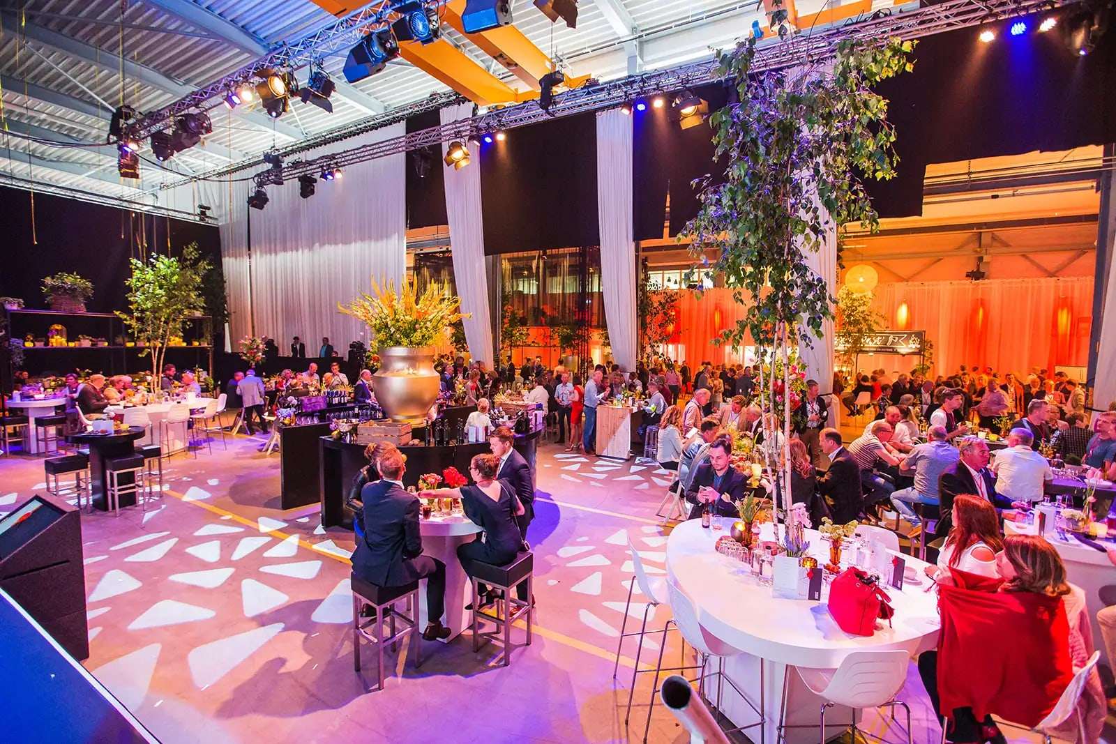 Groot evenement op locatie met podium, verlichting en gedekte tafels