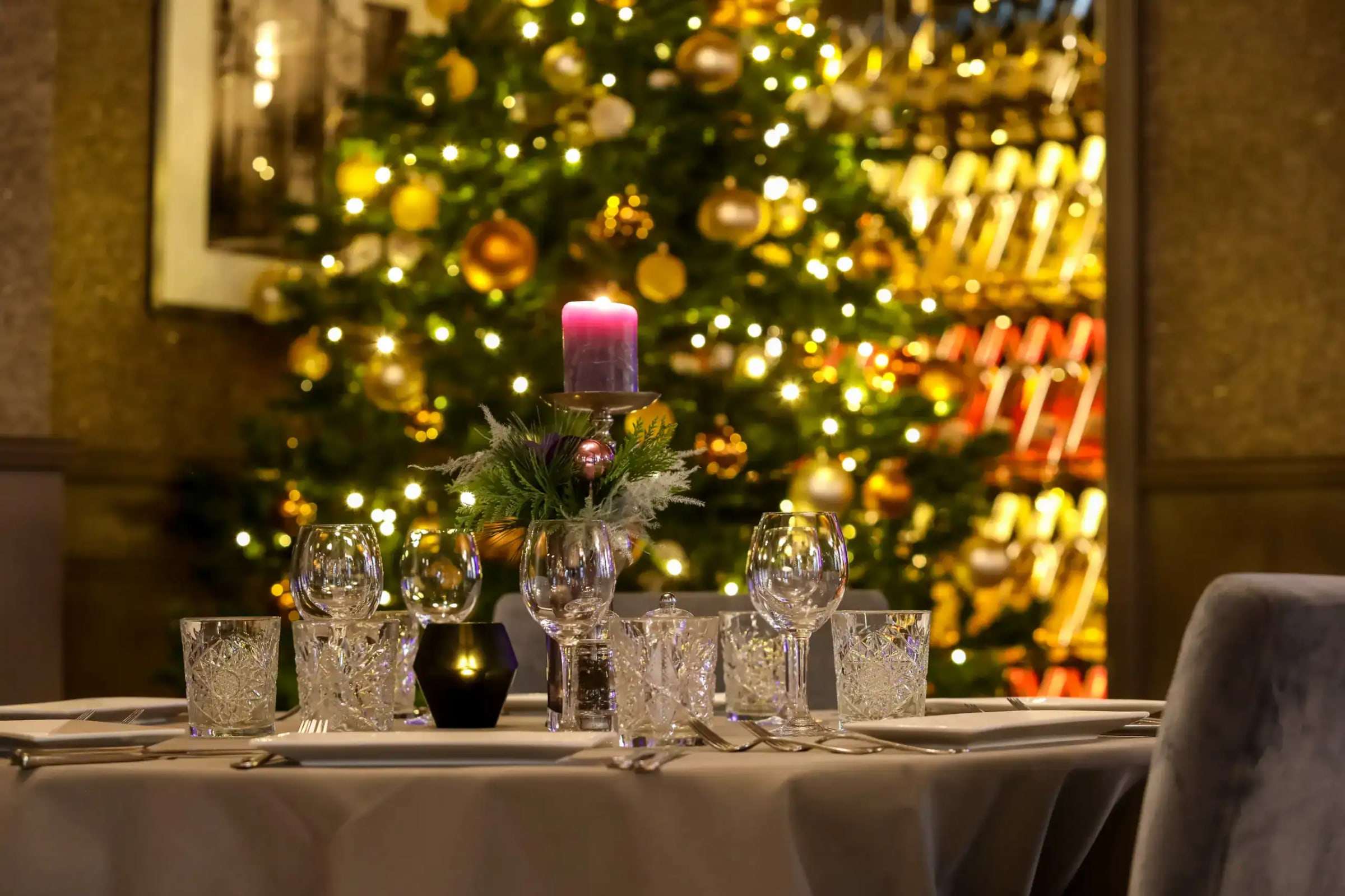 Kerstboom met lichtjes naast een gedekte tafel