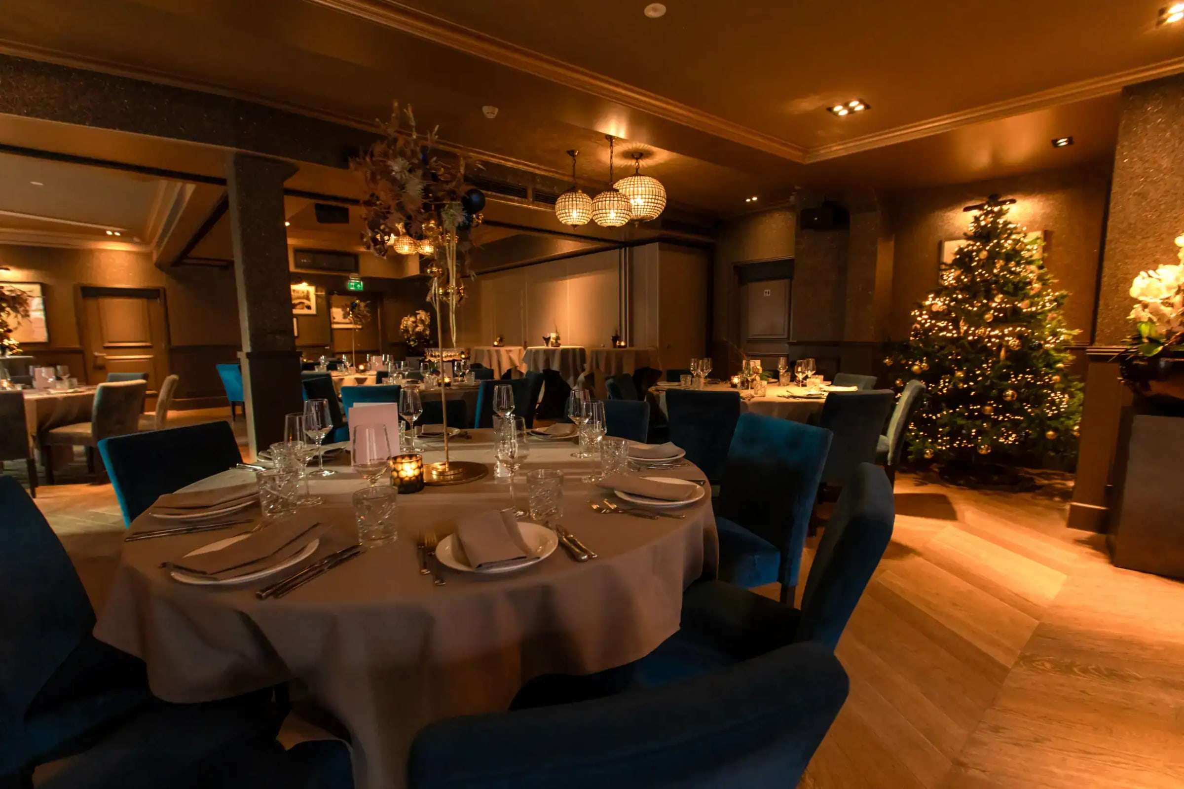 Zaal in kerstsfeer met gedekte tafels voor een zakelijk kerstdiner