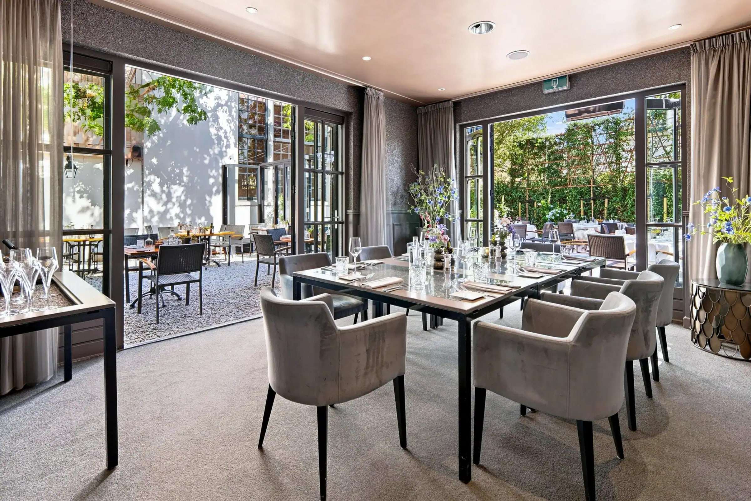 Terraszaal met gedekte tafel en grote glazen deuren naar het terras