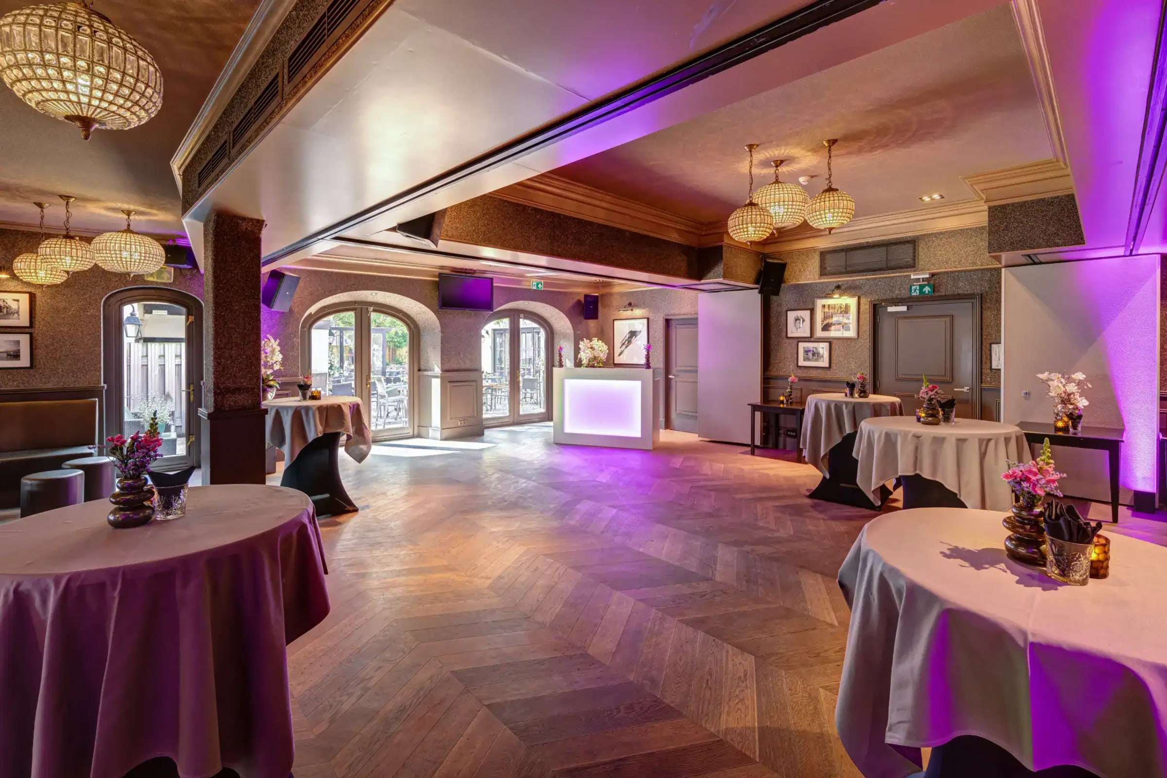 Tuinzaal in feestopstelling met statafels, sfeerverlichting en DJ-booth